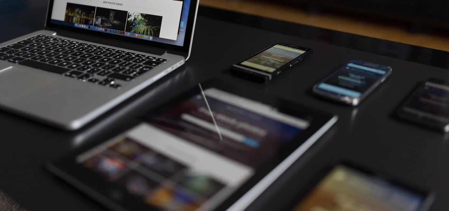 Ordinateur portable, tablette et smartphones affichant le même site internet sur un bureau sombre
